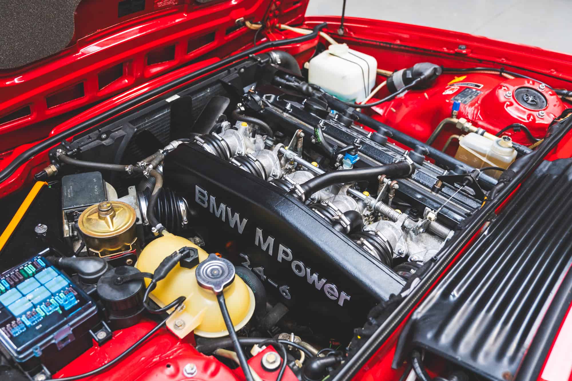 Engine bay of E24 M635 Highline CSL in Zinnober Red.