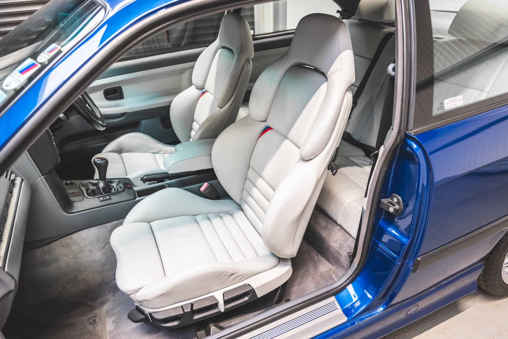 E36 M3 coupe passenger front seat in Hell Grey Leather with manual gearbox and black sports steering wheel.