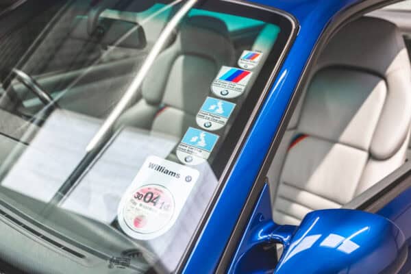 Close up nearside tinted windscreen BMW car club and tax disc on concourse winning E36 M3.