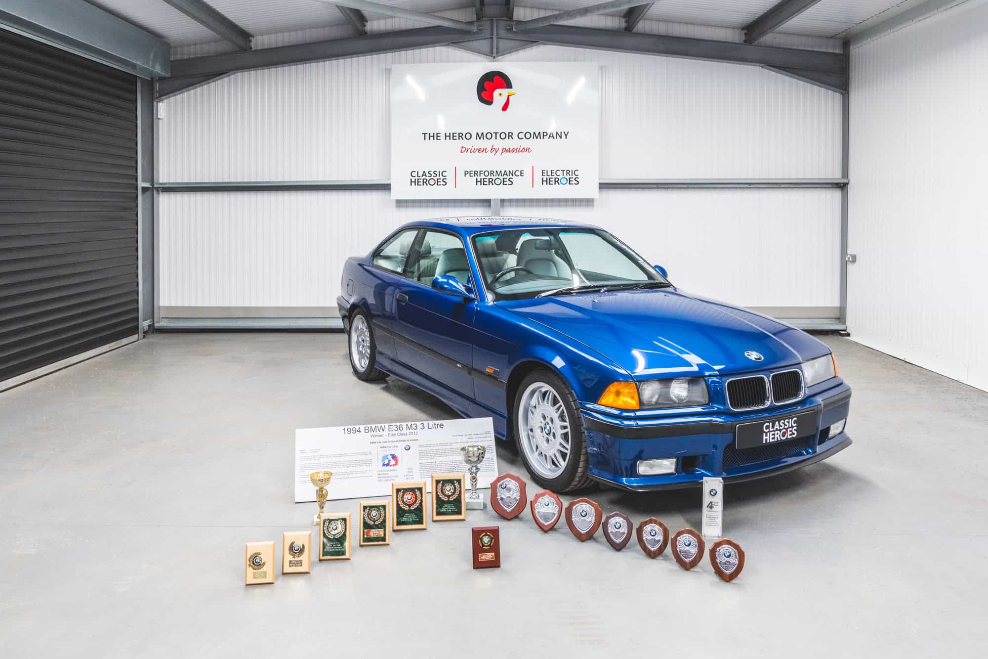 BMW E36 M3 concourse winning classic in Avus Blue surrounded by trophies from its winning history.