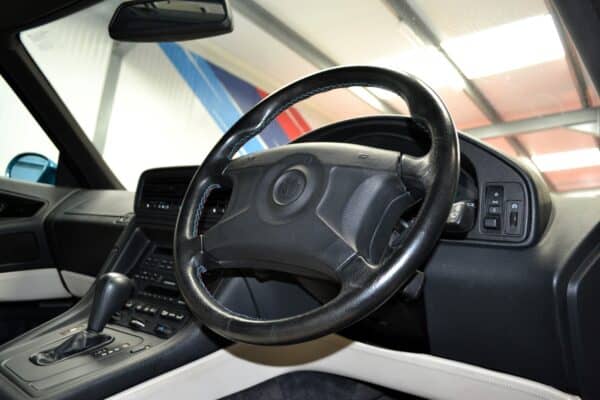 Drivers side interior view of a BMW E31 840 Ci black leather dashboard and automatic gearbox lever.