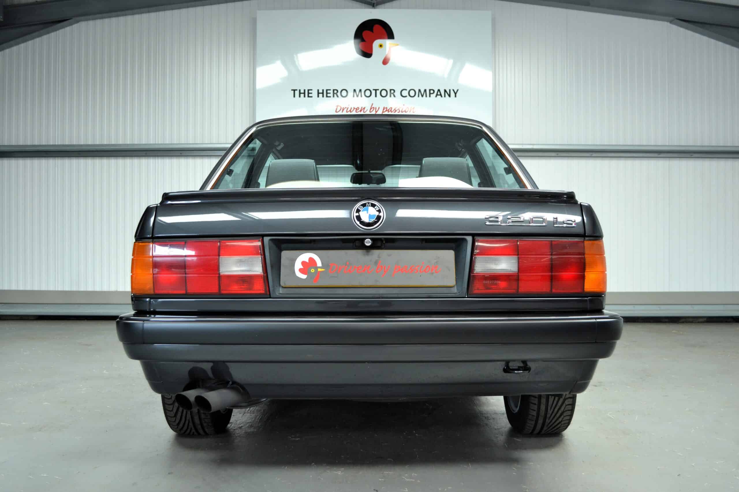 Rear end of an E30 320is in Diamond Black with boot spoiler and BMW badge exhaust.