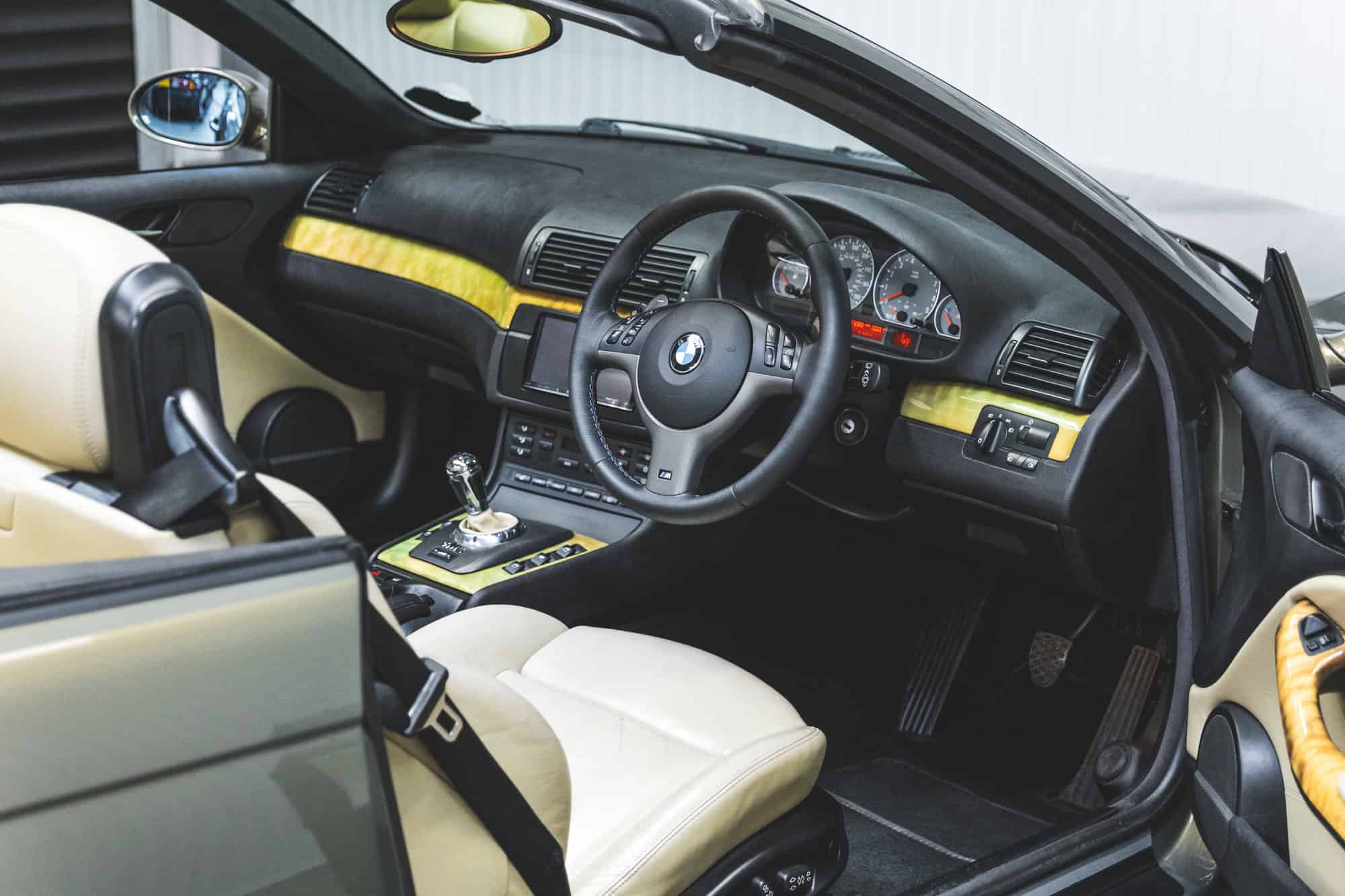 Drivers side view of a BMW E46 M3 Convertible black dashboard with individual wood trim.