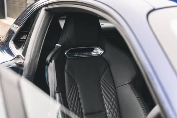 Alpine badge on black leather drivers seat in Renault Alpine.