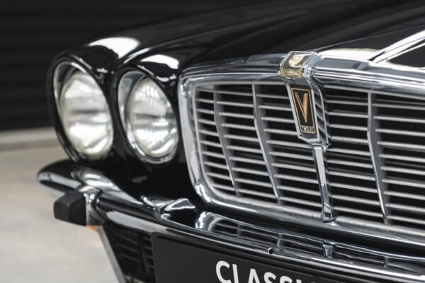 Close up exterior view of headlight and chrome bumper on Gloss Black Jaguar XJC V12 Coupe Sports Saloon.