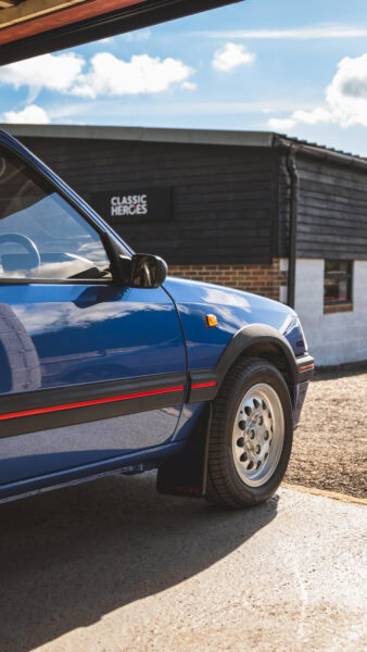 A 1.6 8v Peugeot 205 GTI in Miami Blue with pepper pot alloy wheels in storage at Hero Motor Company.