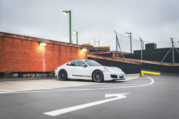 A white Porsche 991 Carrera T with grey alloy wheels parked at night on a rooftop car park in Tunbridge Wells.