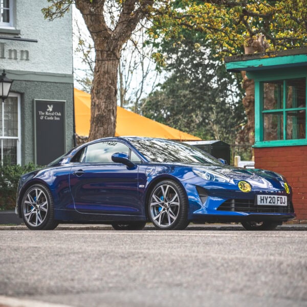 An Abysse Blue Renault Alpine A110 GT sports car at the Oak and Castle Inn outside Pevensey Castle in square crop.