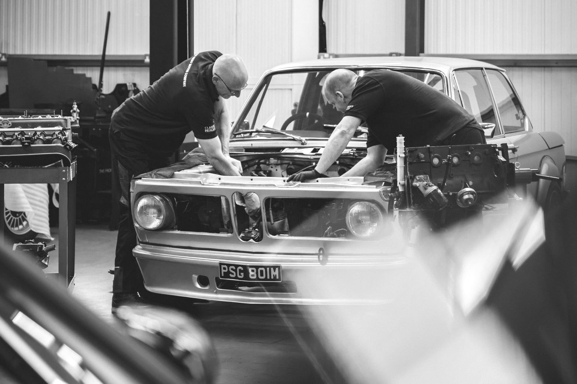 Two specialist BMW mechanics servicing a 2002 tii classic car and performing an engine removal and rebuild in a well equipped workshop in East Sussex.