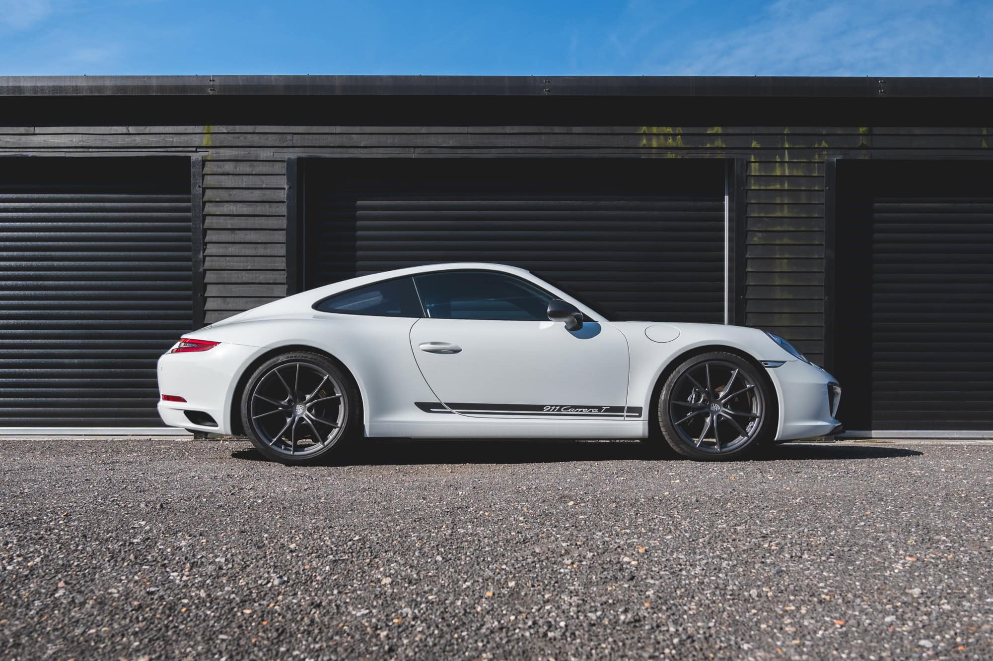 Nearside exterior of Pure White Porsche 991 Carrera T showing alloy wheels and decals.