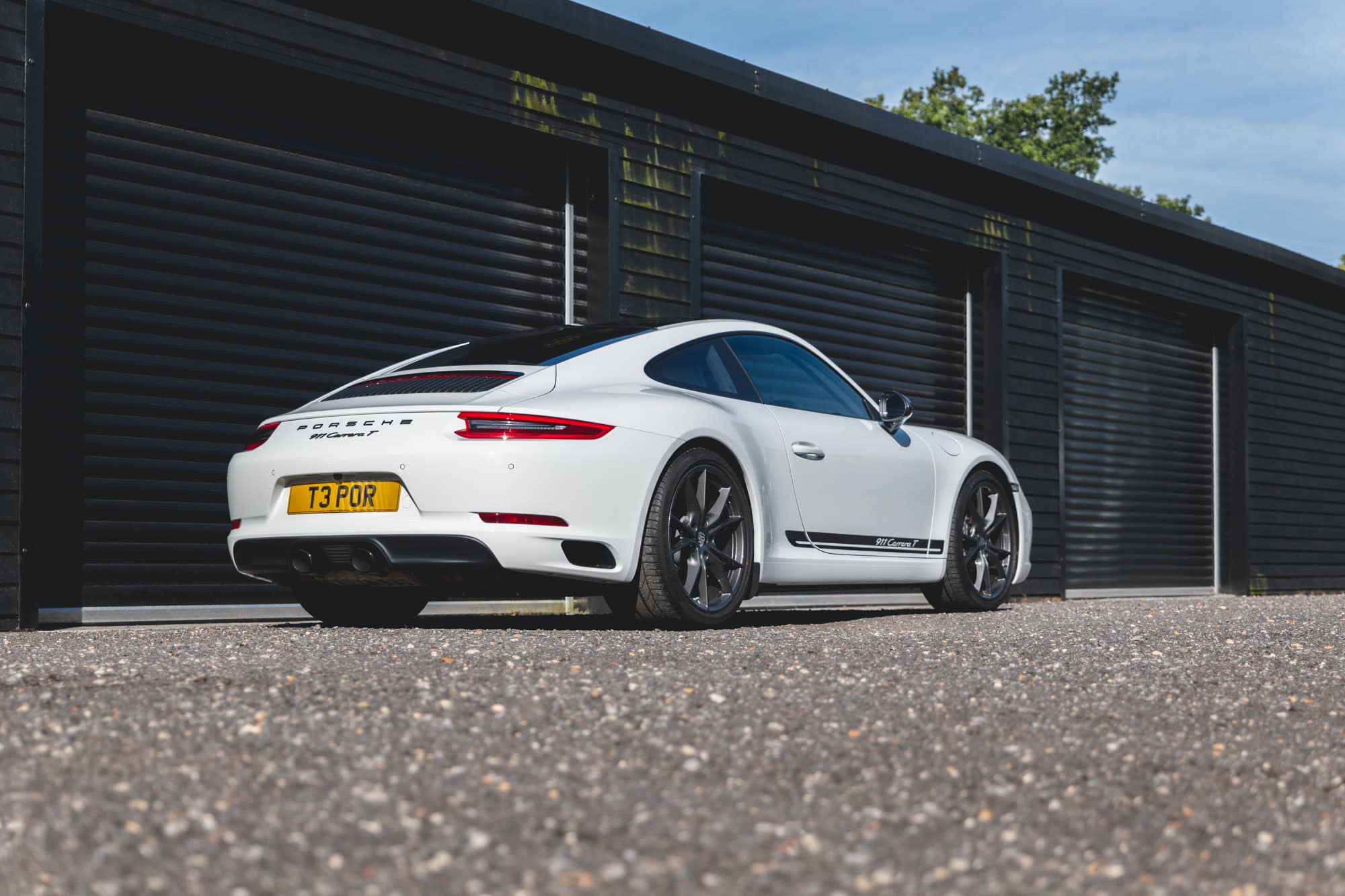 Rear offside exterior of Pure White Porsche 991 Carrera T showing alloy wheels and exhaust.