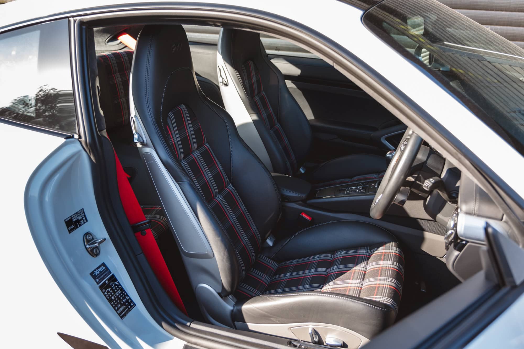Offside view into interior of Porsche 991 Carrera T and black leather with tartan material inserts.