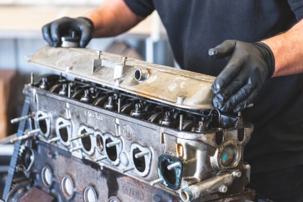 A skilled and experienced mechanic removes the cam cover off a BMW engine to rebuild and make more power.