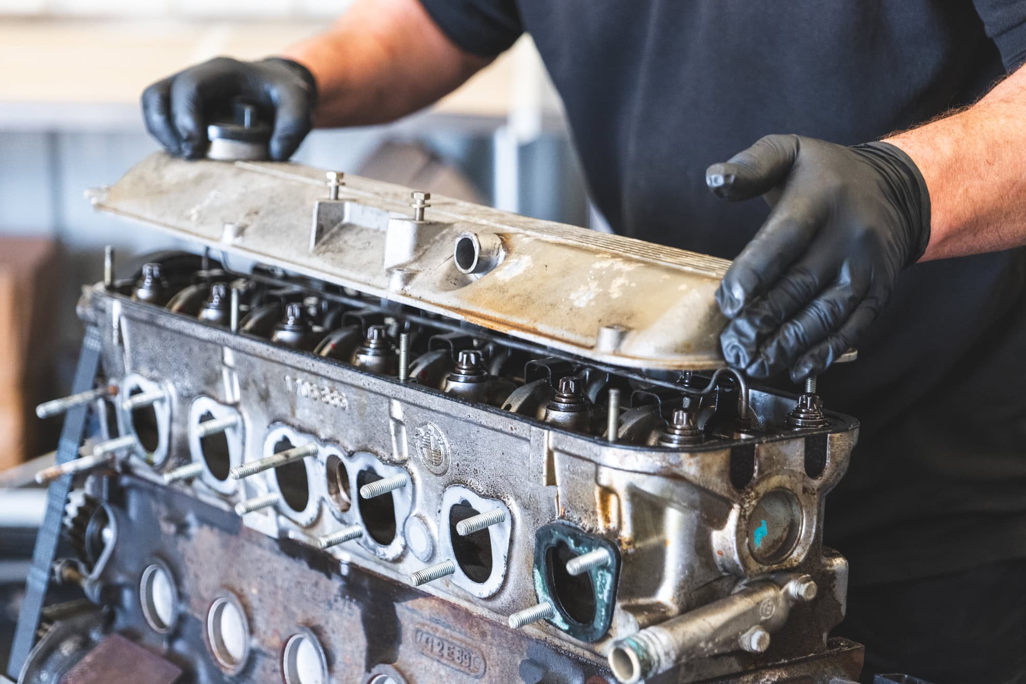 A skilled and experienced mechanic removes the cam cover off a BMW engine to rebuild and make more power.