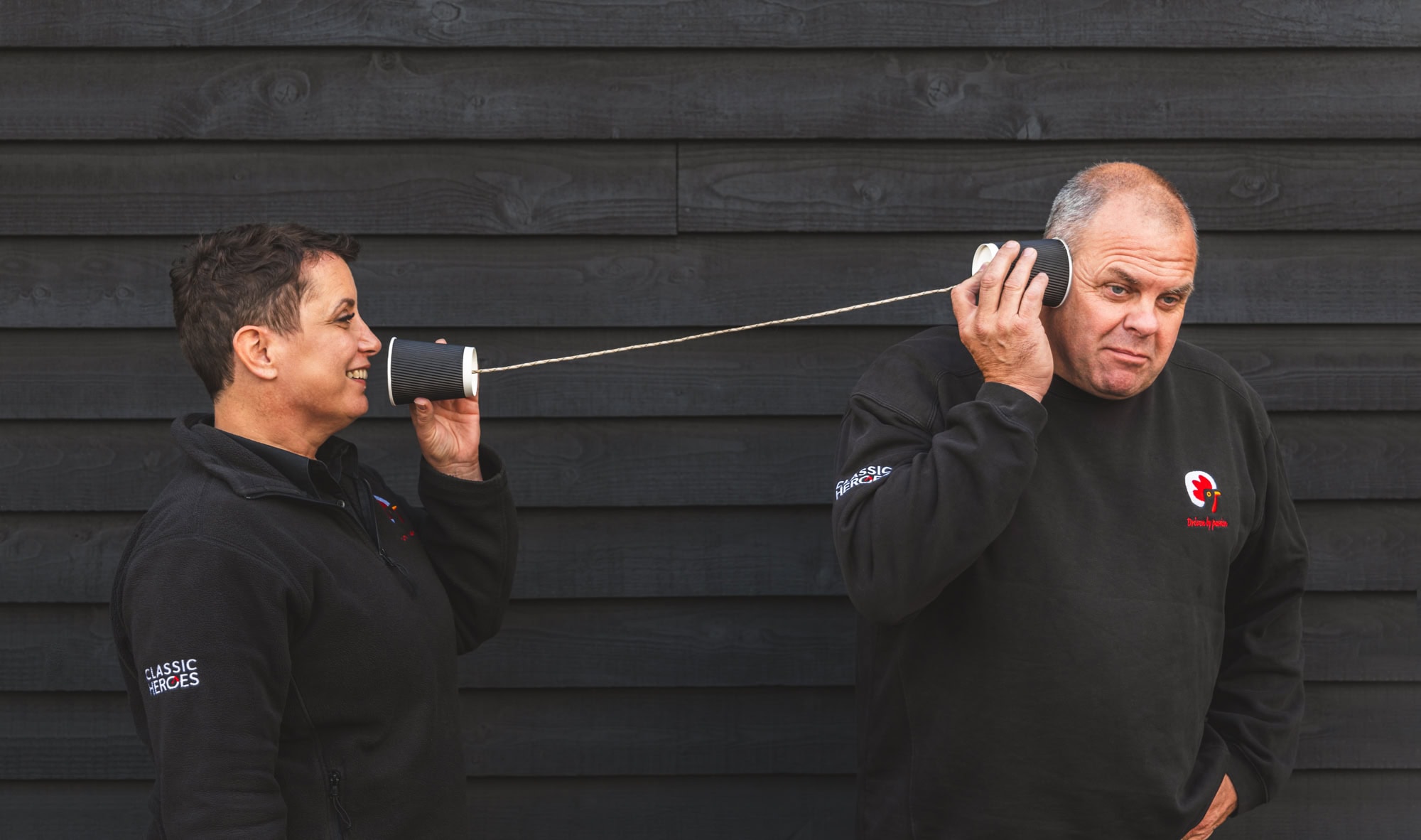 Barney Halse holds a paper cup walkie talkie to his ear as Teresa talks into the other end.