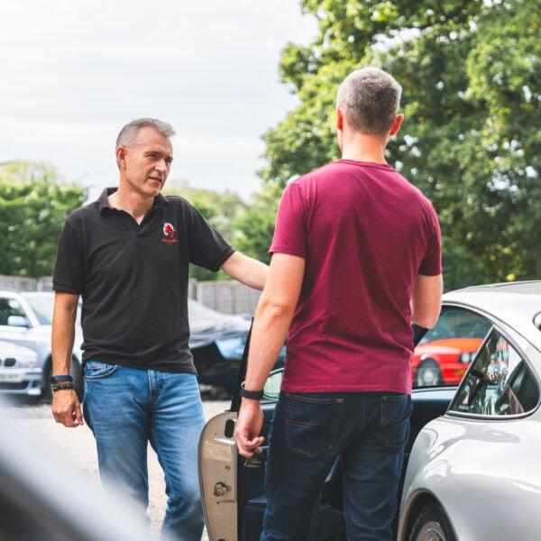 Jack shows a silver Porsche 993 to a young working professional car enthusiast.