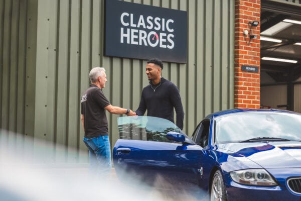 Jack hands over the keys to a blue BMW Z4M Coupe to a young professional.