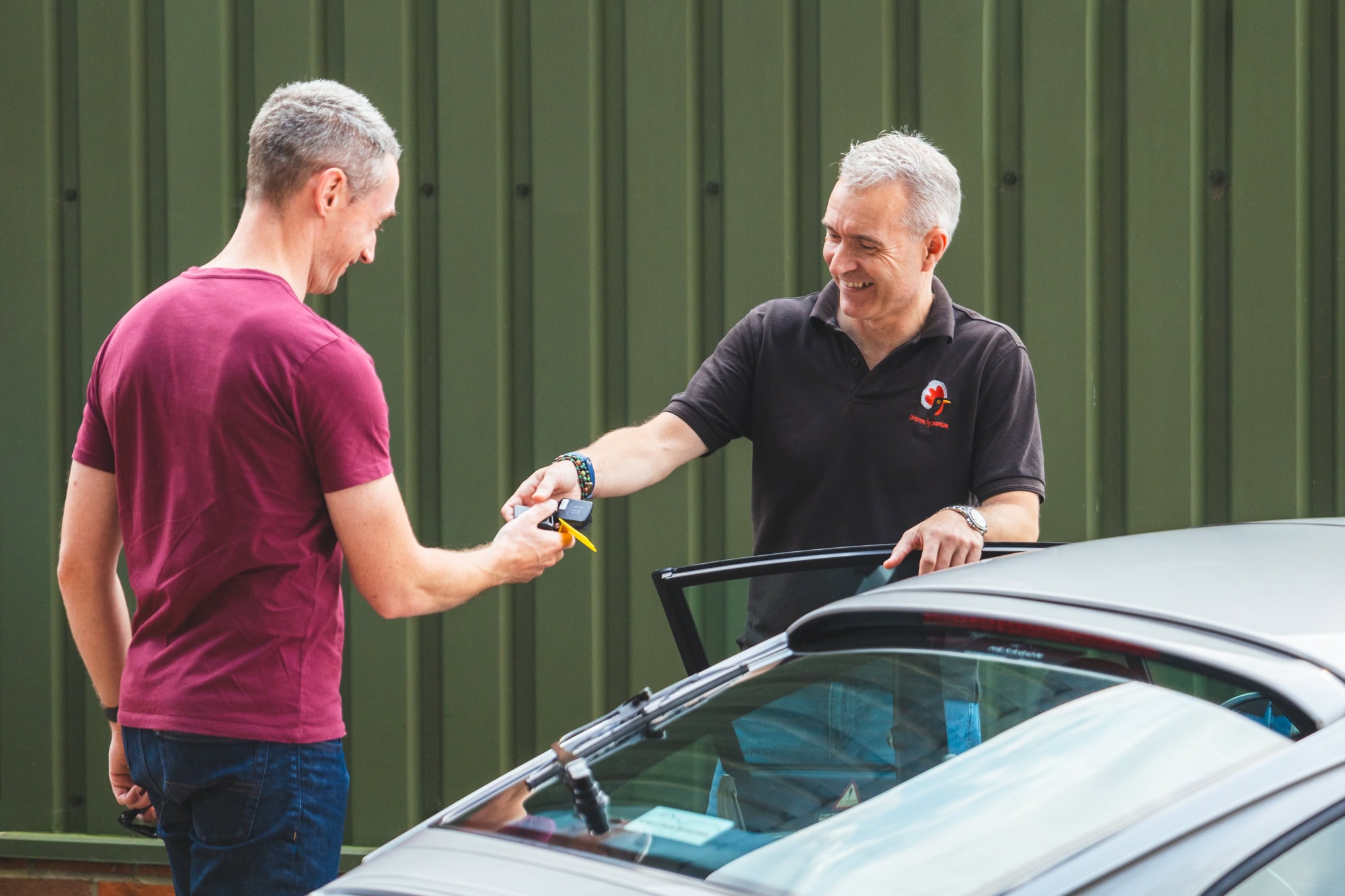 Jack hands over keys for a silver Porsche 993 to a young professional customer.