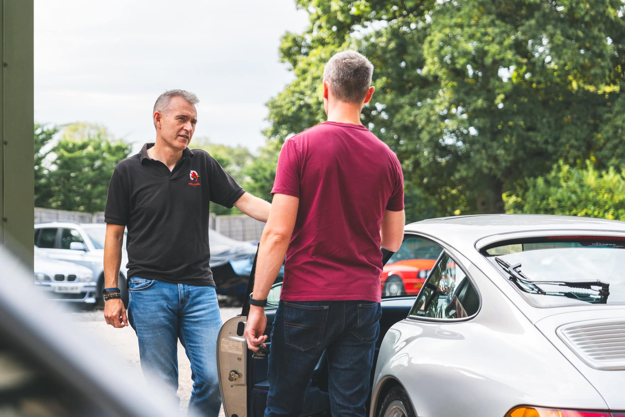 Jack shows a silver Porsche 993 to a young working professional car enthusiast.