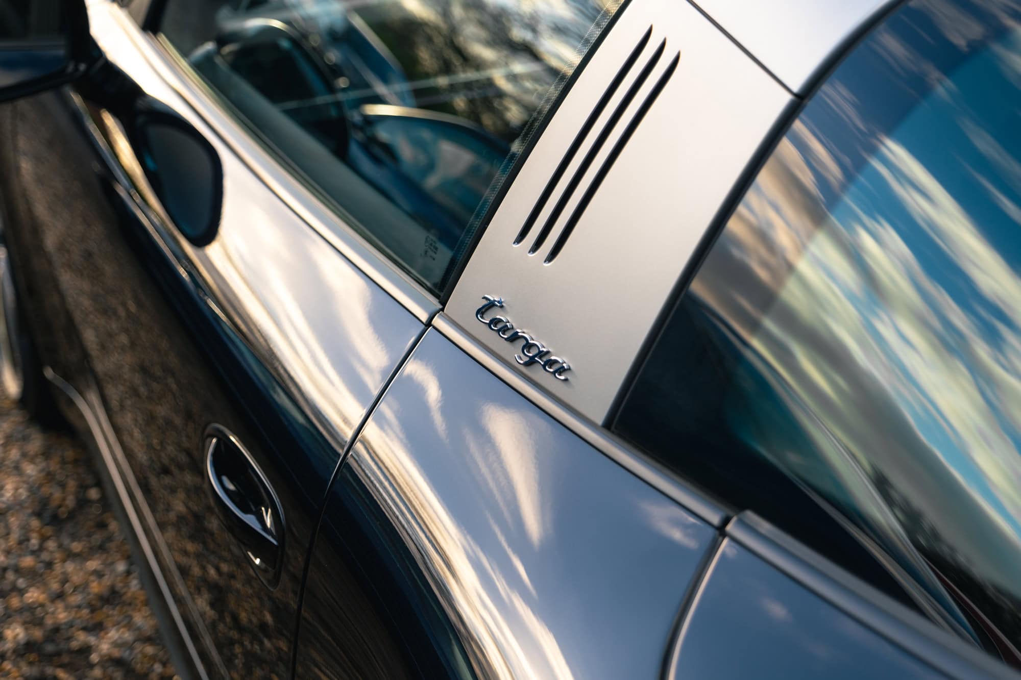 A black Porsche 991 Targa pillar detail showing the brushed aluminium and badge.