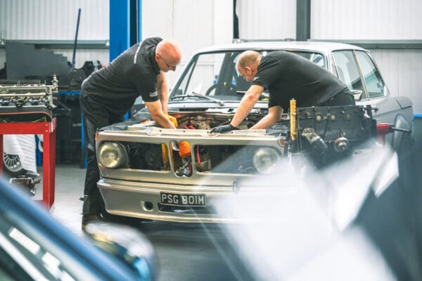 Two specialist BMW mechanics servicing a 2002 tii classic car and performing an engine removal and rebuild in a well equipped workshop in East Sussex.