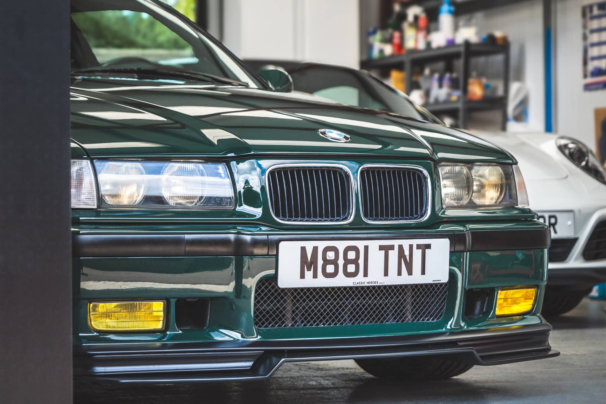 A British racing green BMW E36 M3 GT emerging from the hero motor company valeting bay.