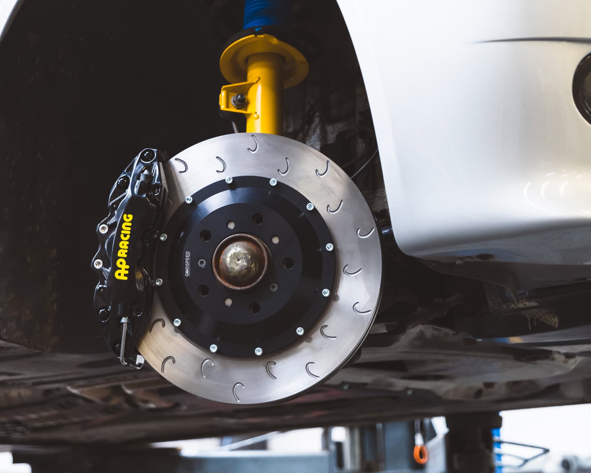 An E46 M3 wheel arch with black AP Racing brake calipers vented discs and Bilstein suspension.