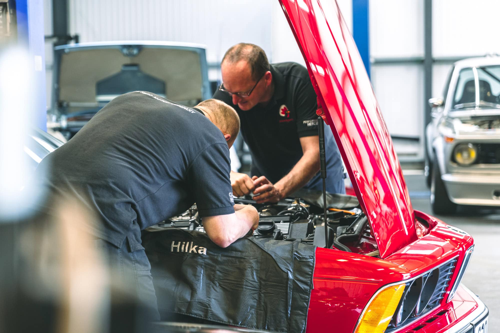 Two specialist mechanics diagnose an electrical issue on a classic BMW M635.