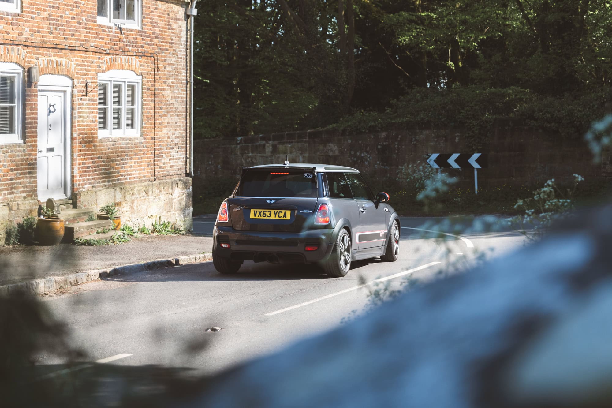 A grey Mini GP 2 Cooper S drives around a fast corner in a rural village.