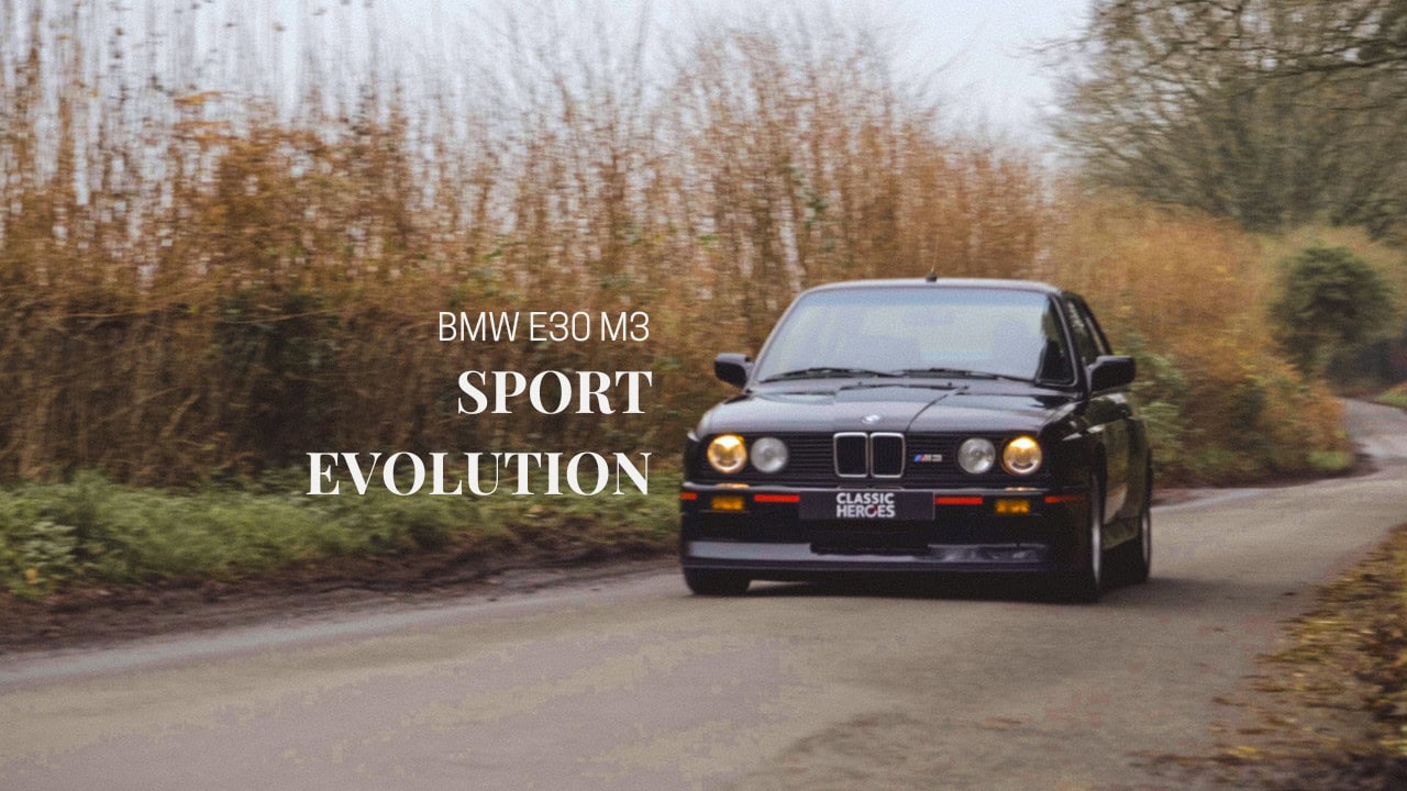 A black BMW E30 M3 Sport Evolution driving down a country road.