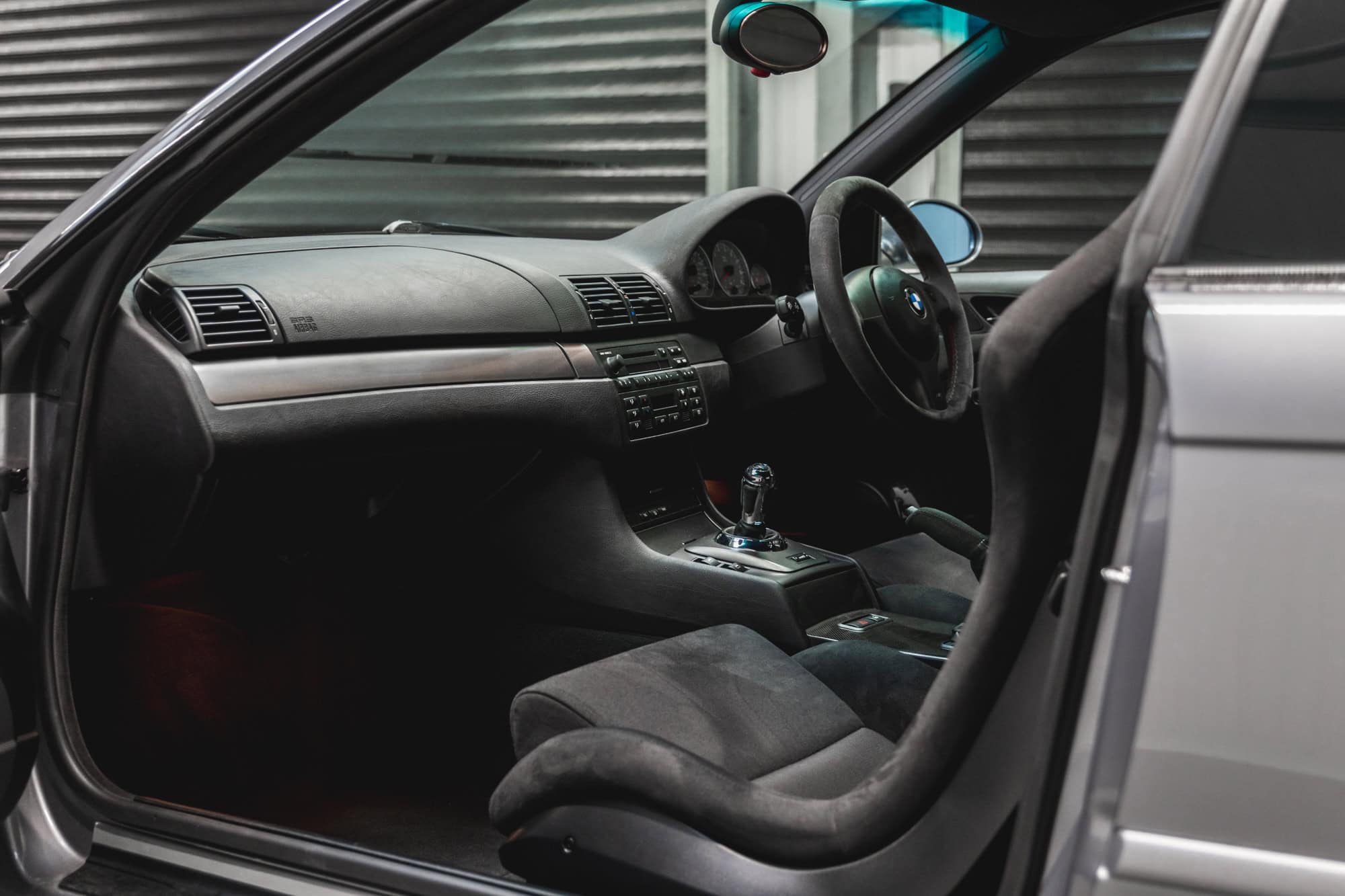 Passenger side view of a BMW E46 M3 CSL dashboard and steering wheel.