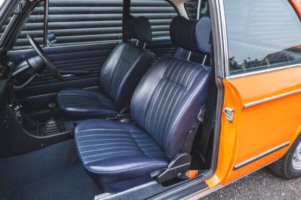 Nearside interior showing leather interior and steering wheel on BMW 2002 tii Inka Orange.