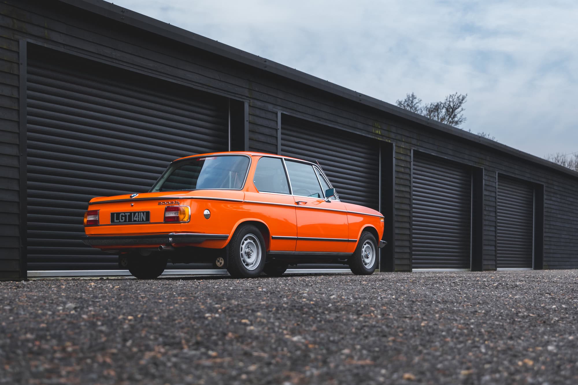 Offside rear exterior showing chrome and wheels on BMW 2002 tii Inka Orange.