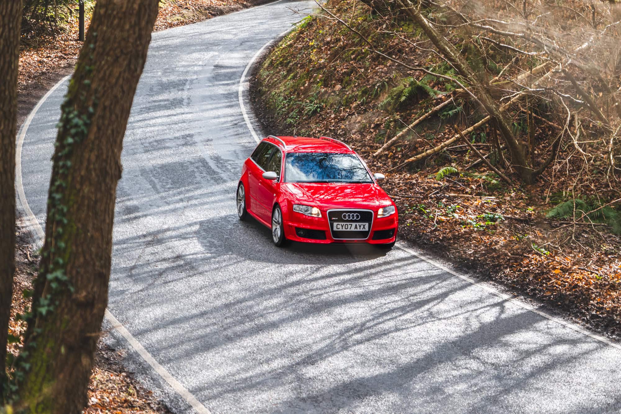A red Audi RS4 avant driving down a curved first road.