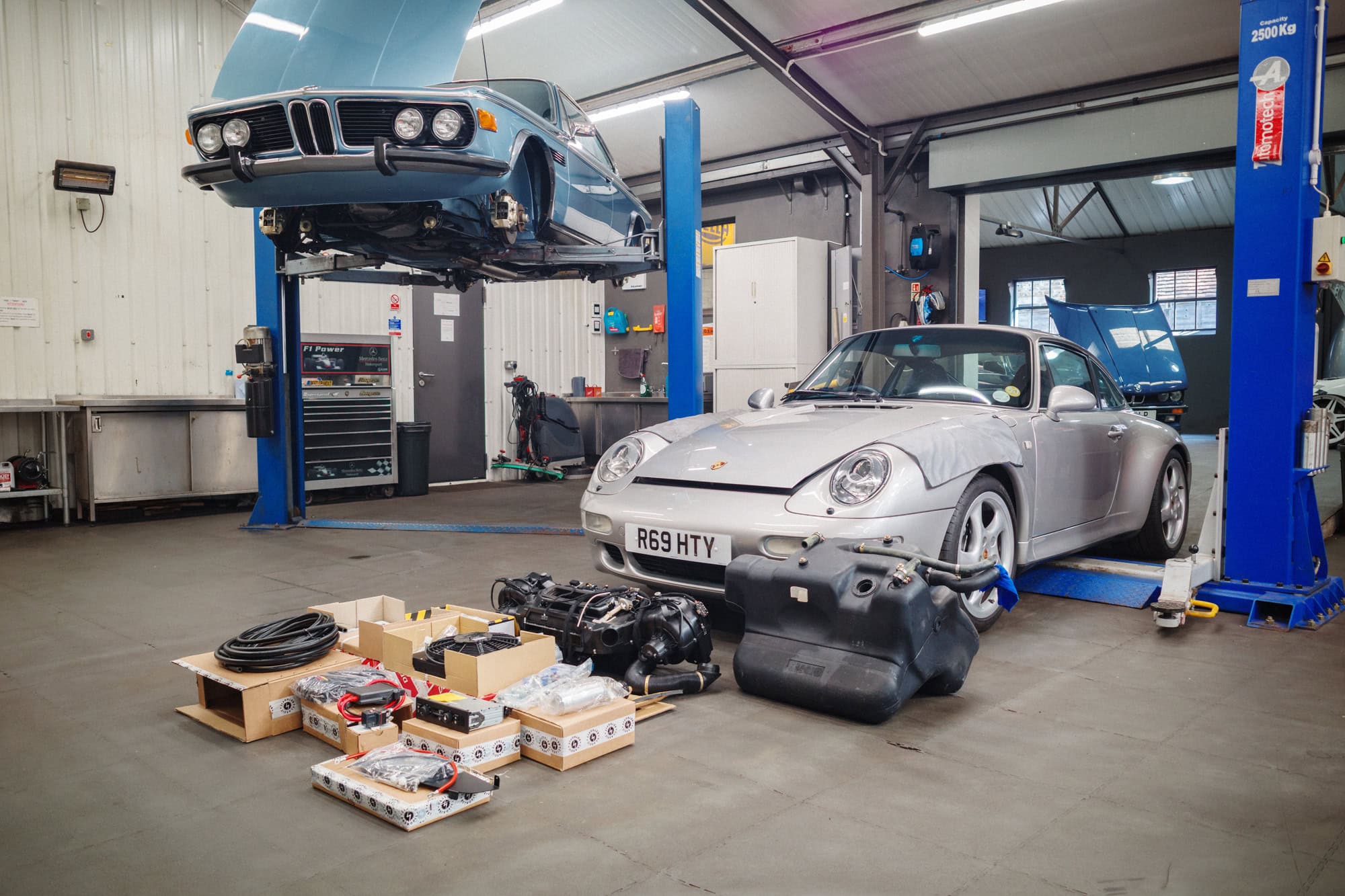 A silver Porsche 993 in the workshop with components for fitting air conditioning.