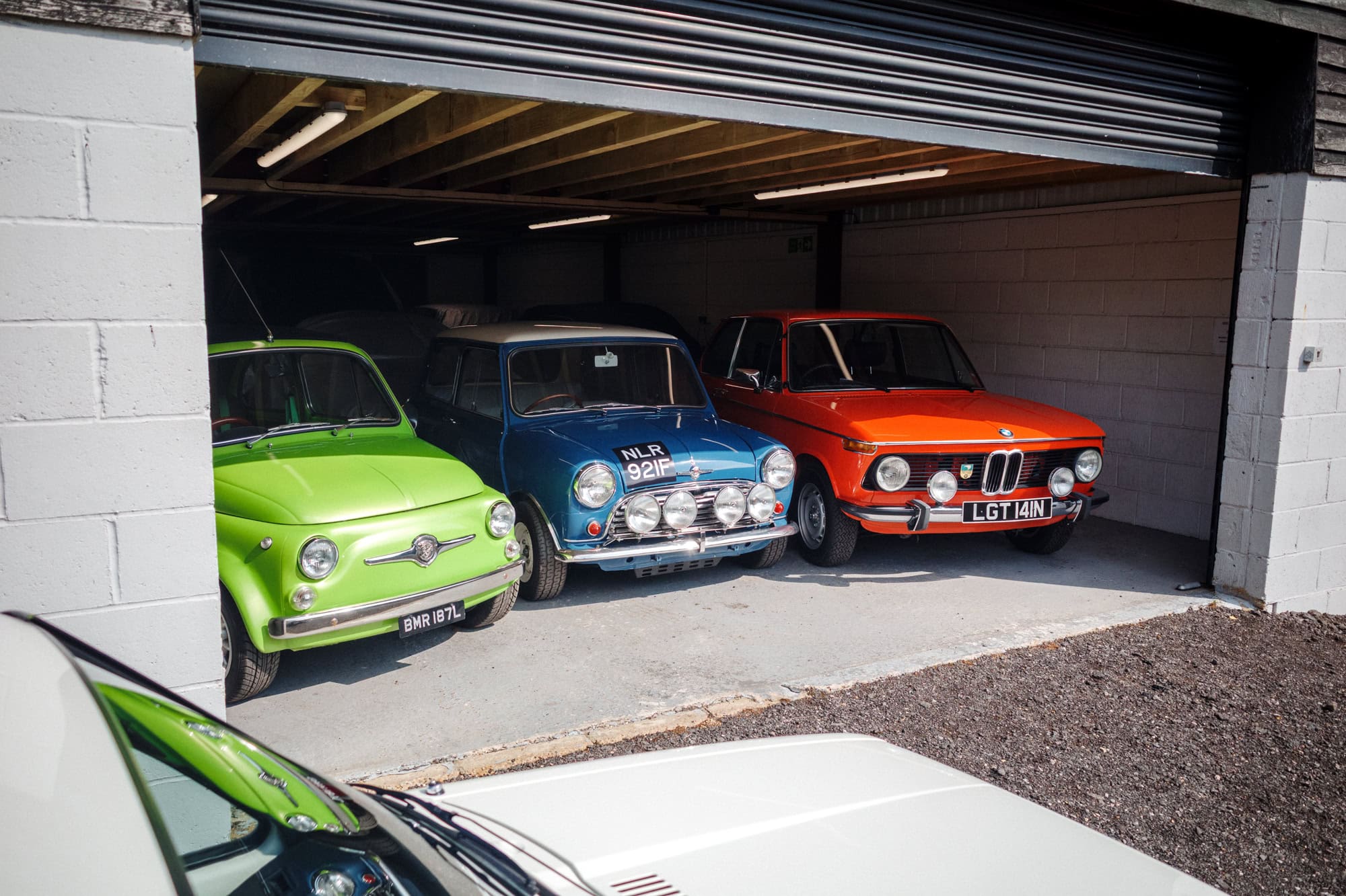 A trio of colourful old cars in a garage.