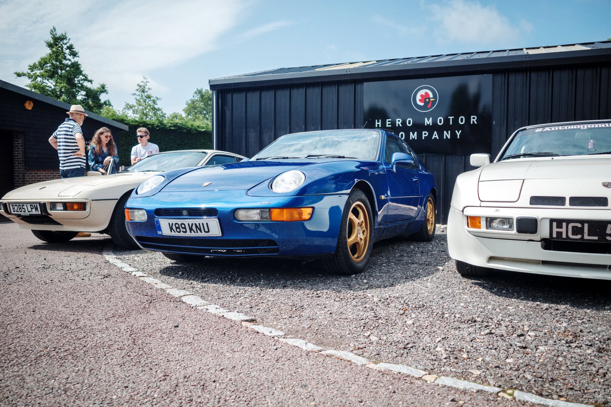 A blue Porsche 968 with gold wheels at a Hero Motor Company open day.
