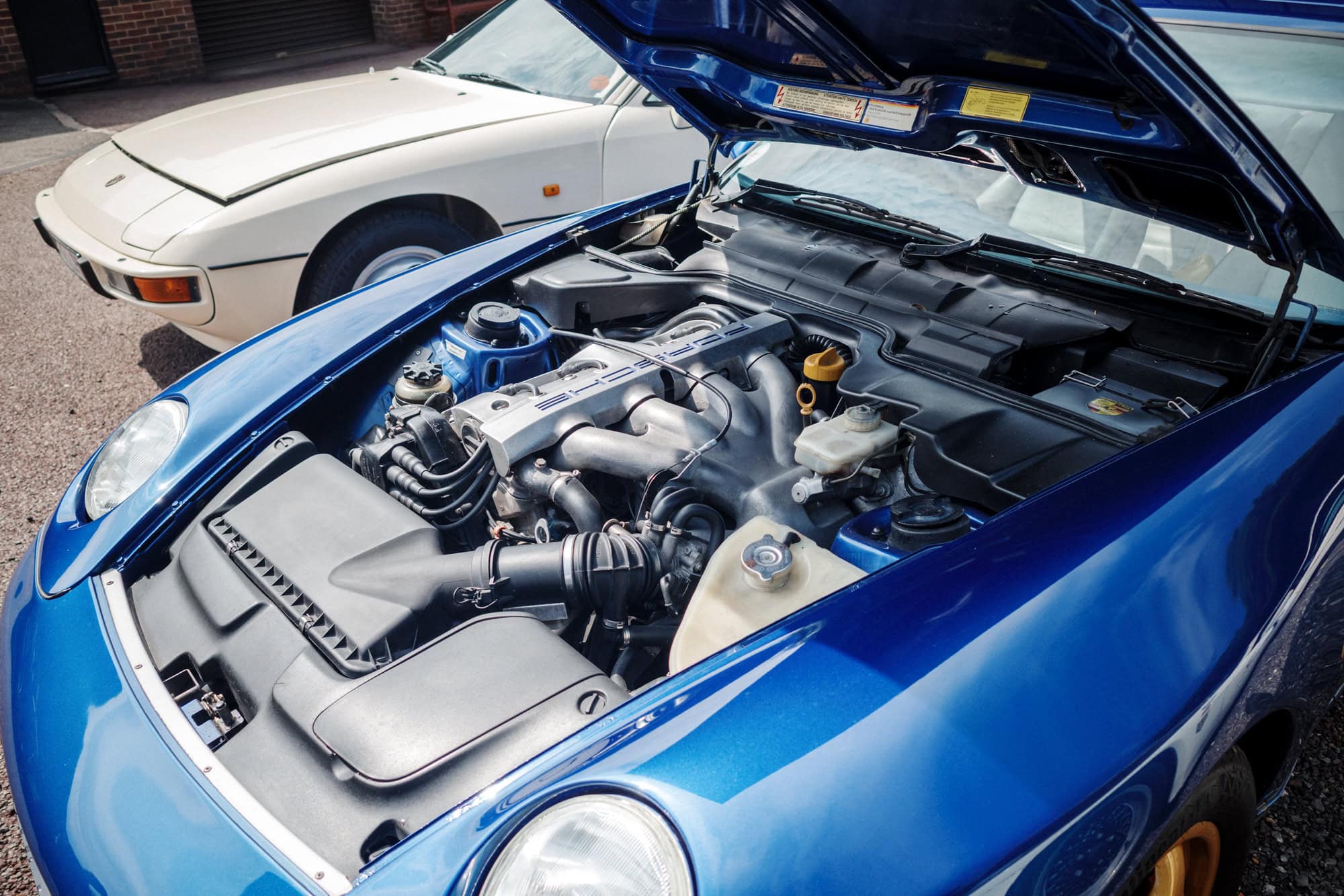 The engine bay of a blue Porsche 968.