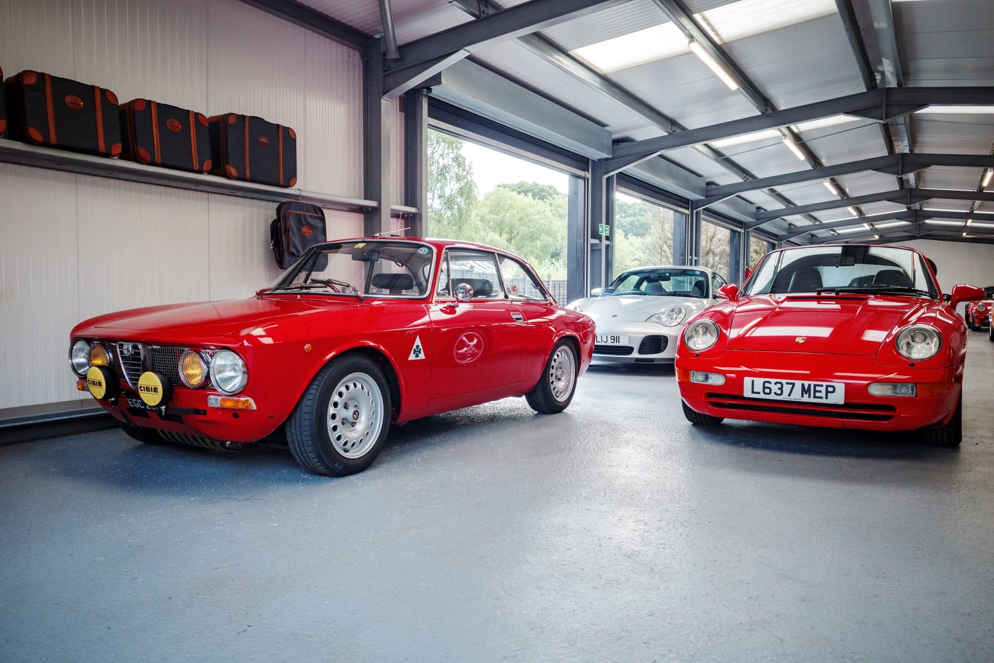A red Porsche 993 and Alfa Romeo on display at an open day.