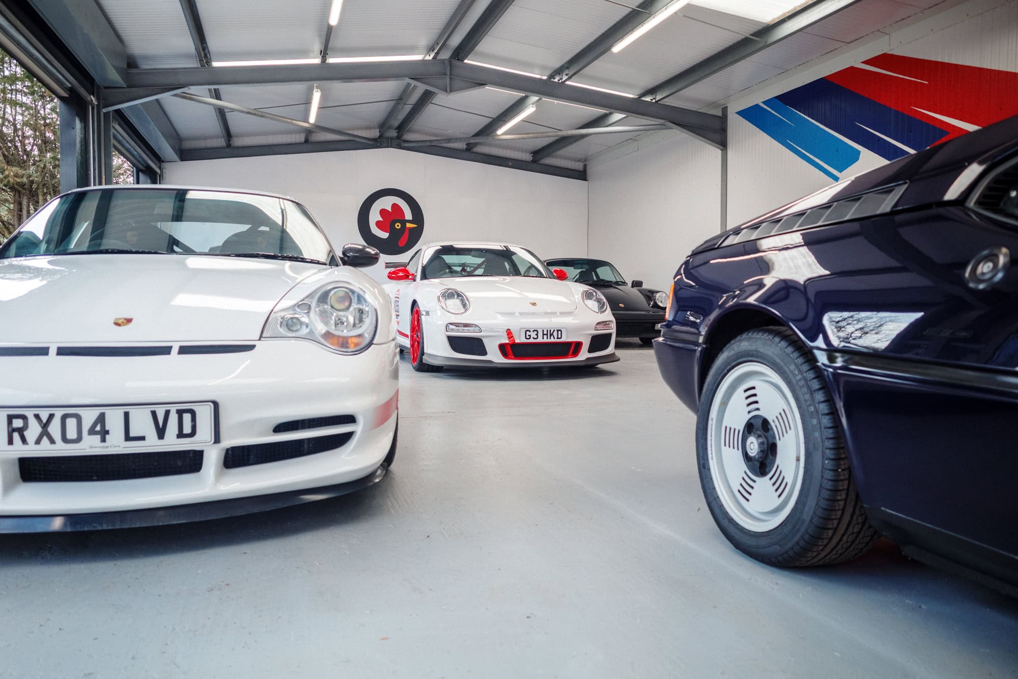 A BMW M1 rear quarter surrounded by Porsche GT3 RS's.