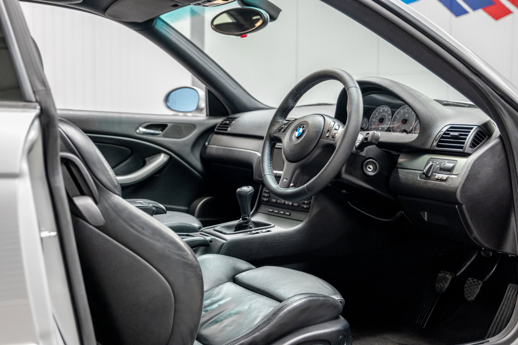 Offside interior view of black leather interior showing steering wheels and centre console on E46 M3