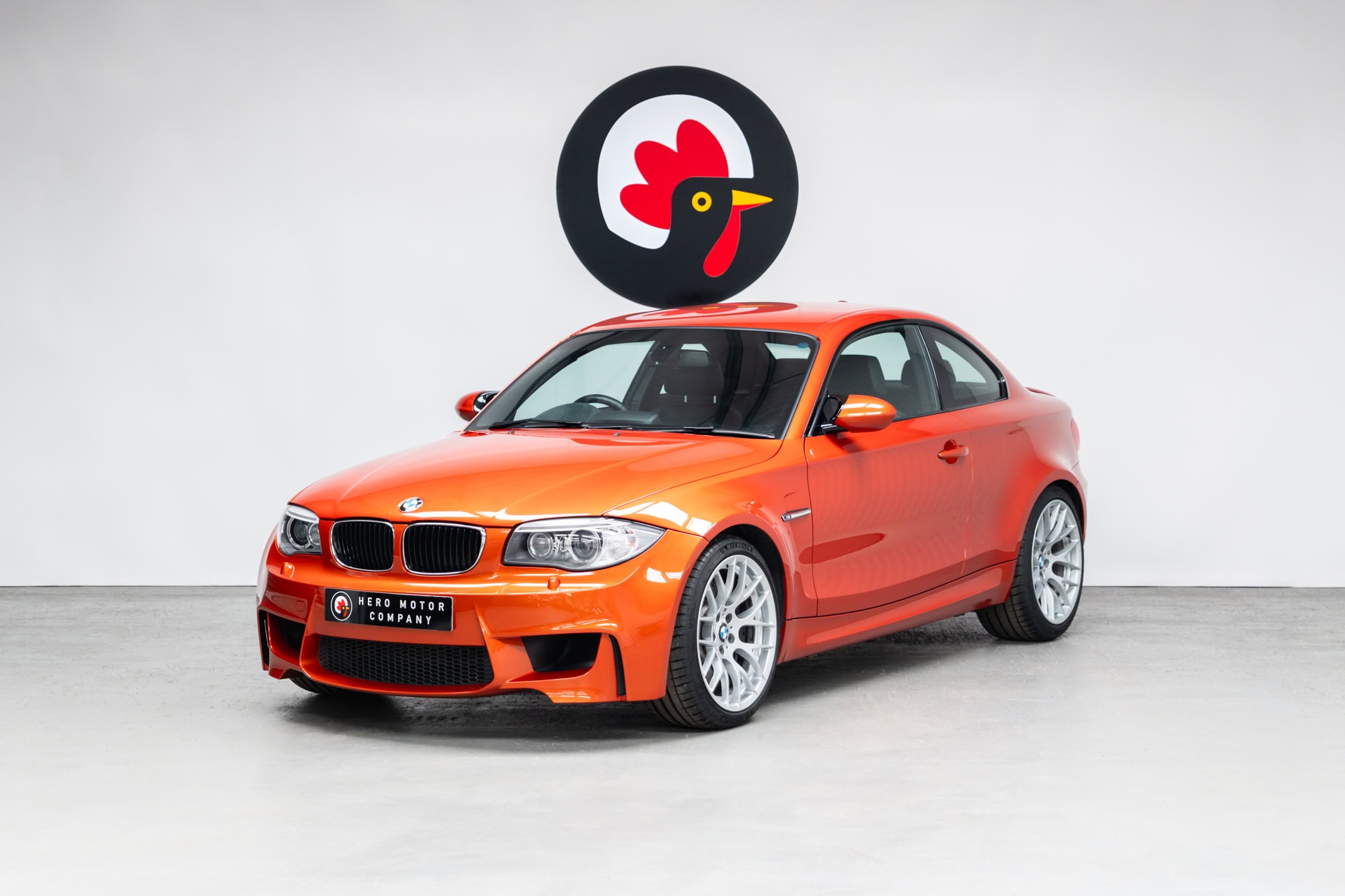 Front nearside exterior view of BMW E82 1M Coupe Valencia Orange showing chrome grill and headlights