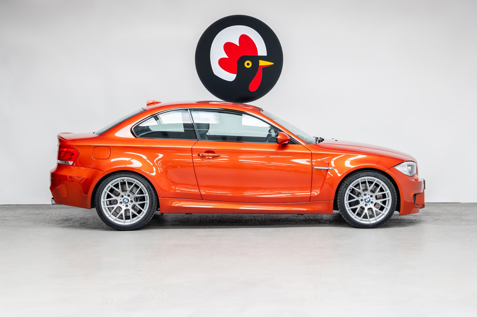 Offside exterior BMW E82 1M Coupe Valencia Orange showing alloy wheels
