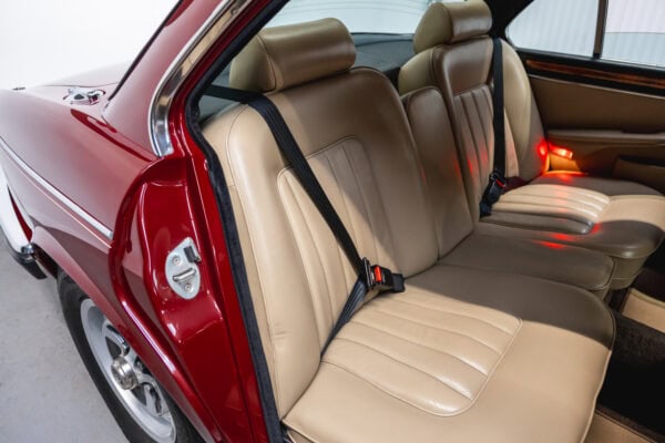 Offside interior view of rear leather seats headrest and seat belts in 1985 Daimler Double Six Bordeaux Red Series 3 Saloon V12