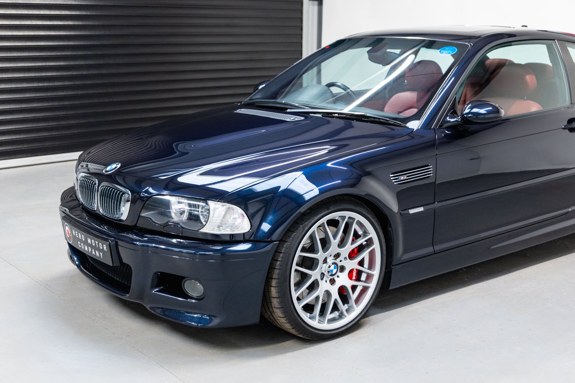 Nearside exterior showing red leather interior on BMW E46 M3 in carbon black with CSL alloy wheels and AP Racing brake Kit on Ohlins suspension with Karbonius CSL Carbon Airbox.