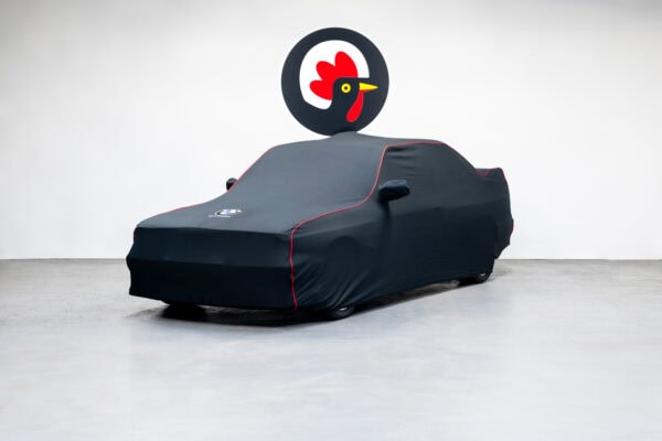 An E30 BMW M3 Sport Evolution for sale under a black car cover.