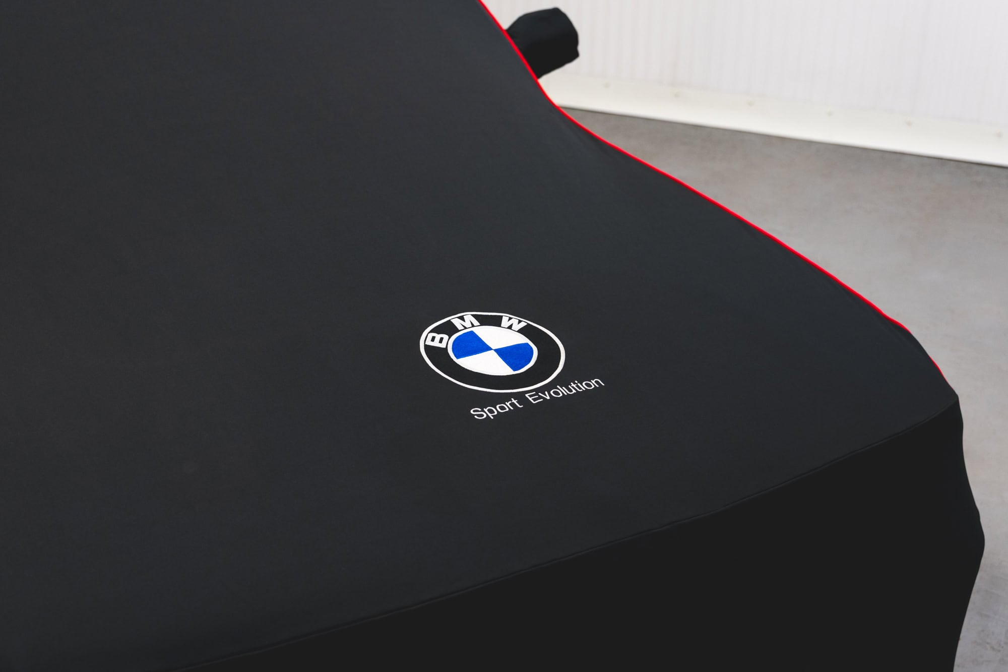 A black BMW E30 M3 Sport Evolution car cover emblem.