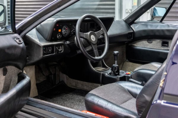 Nearside view into interior of BMW E26 M1 1980 Nicht Blau showing steering wheel centre console and gear stick