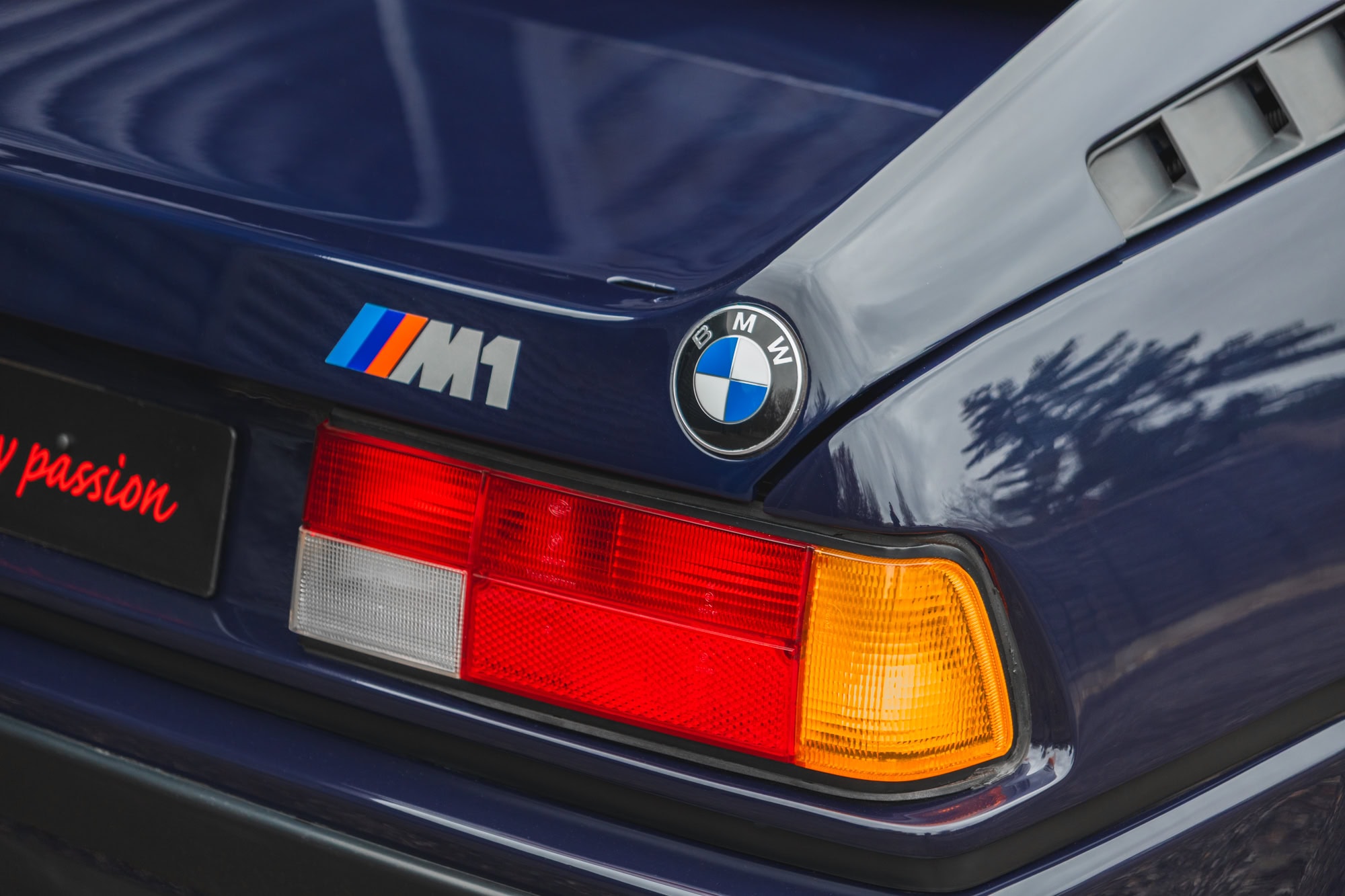 Close up view of M1 BMW badge and rear tail light on 1980 E26 BMW M1 Nachtblau