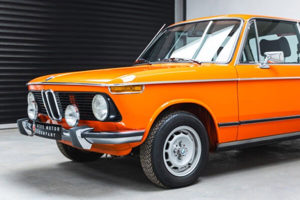 Nearside front quarter of a 1975 BMW 2002 tii in Inka Orange.